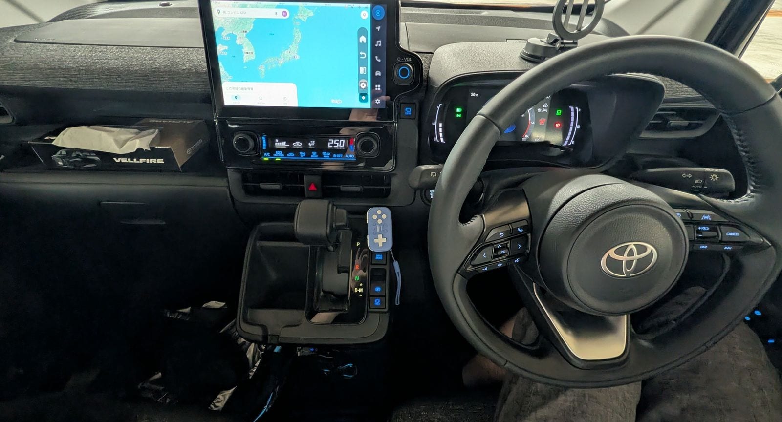 シエンタの運転席まわり。上の画面が Ottocast で Google マップを表示、シフトレバーの横にマジックテープで固定した 8BitDo Micro、右にハンドル